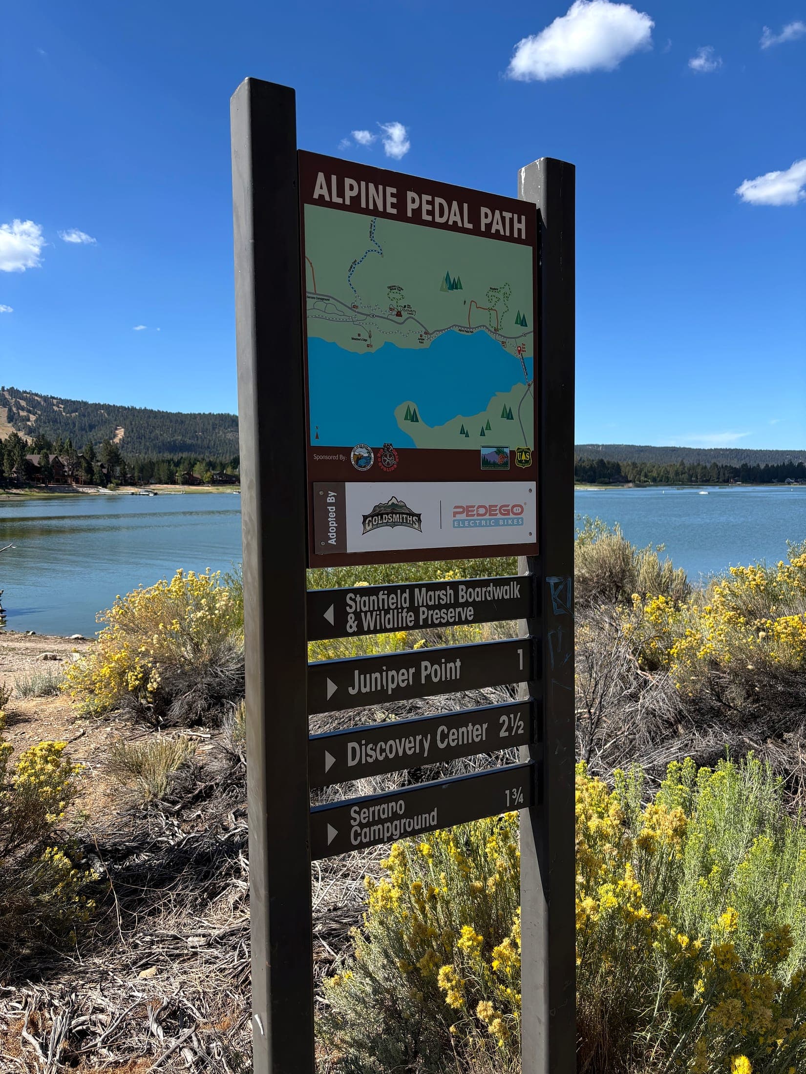 Alpine Pedal Path trail sign at Big Bear Lake listing Stanfield Marsh and nearby trail destinations