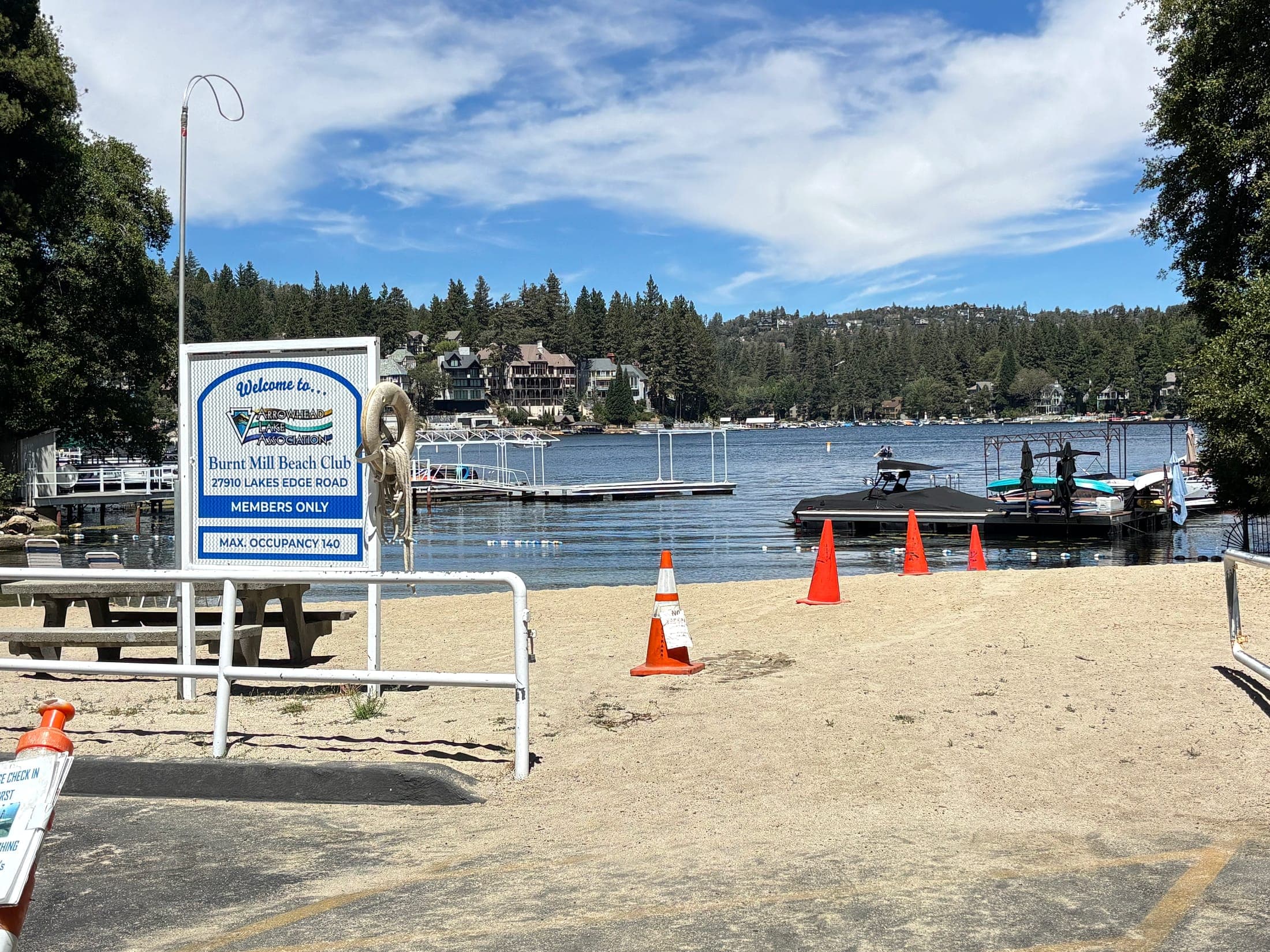 Members-only Burnt Mill Beach Club sign, sand, and boat docks on Lake Arrowhead, California