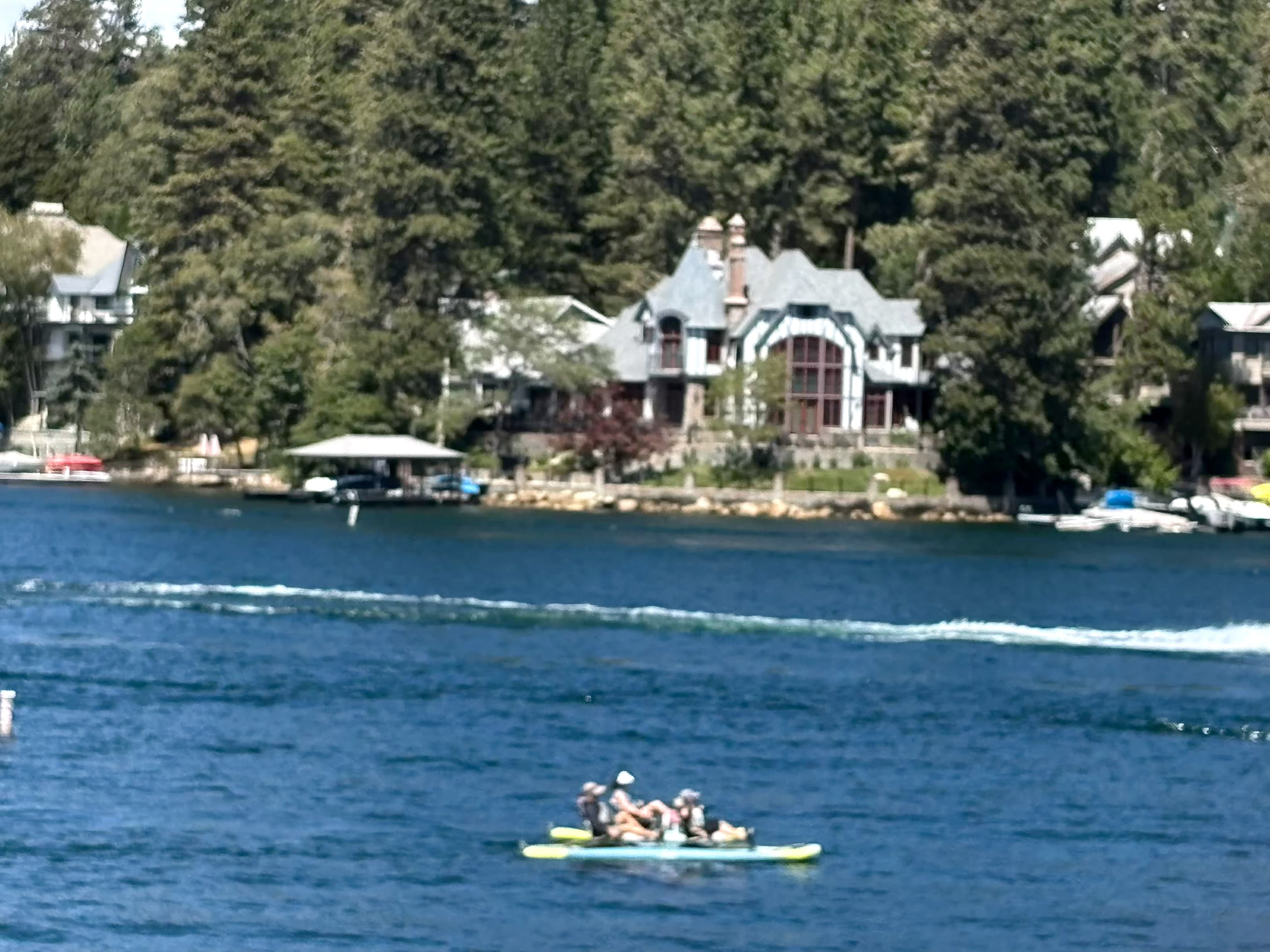 Lakefront house among pines on Lake Arrowhead with a small inflatable in the foreground