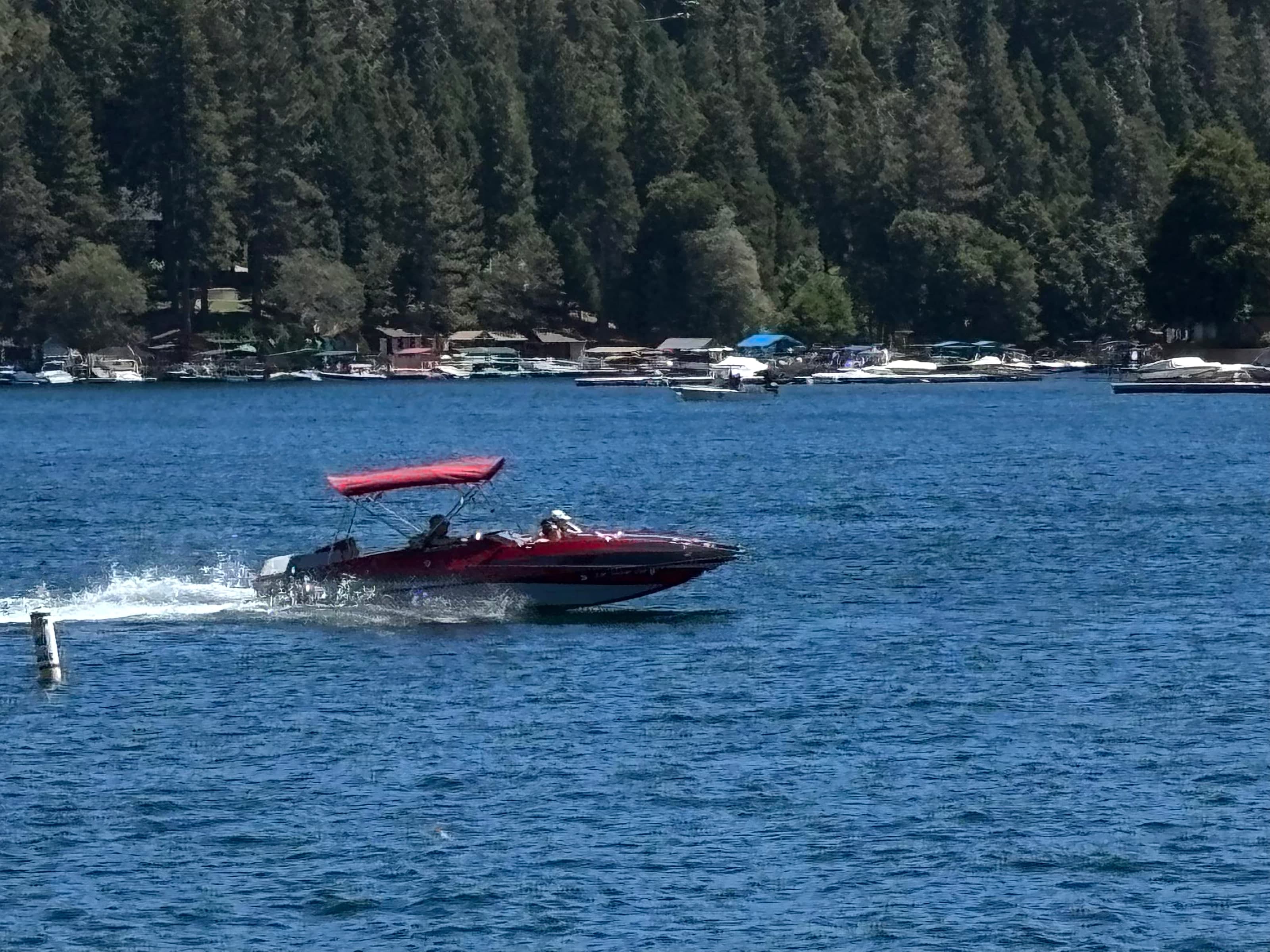 Red motorboat on Lake Arrowhead leaving a wake in front of shoreline docks