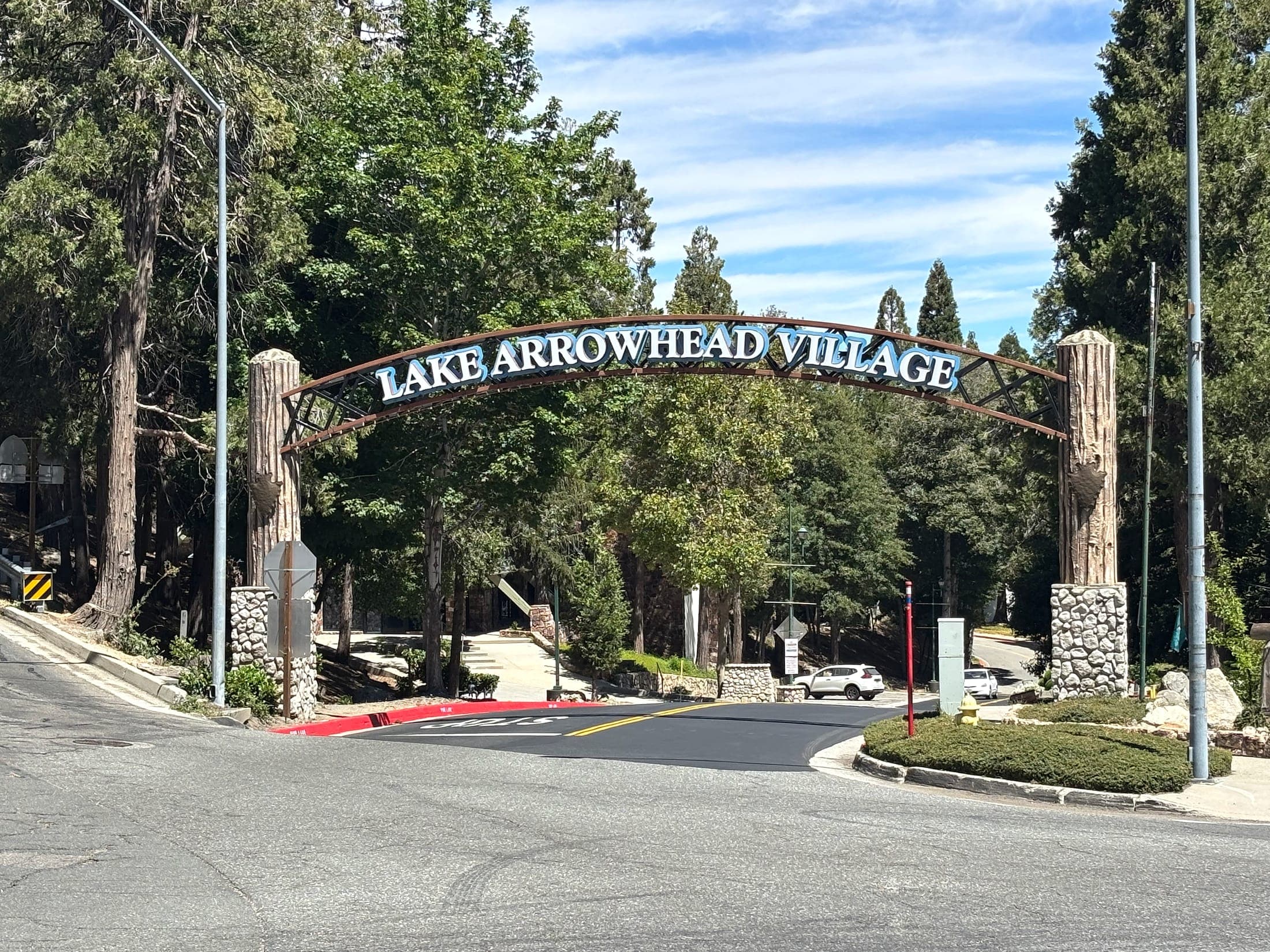 Arched Lake Arrowhead Village entrance sign among pines in the San Bernardino Mountains