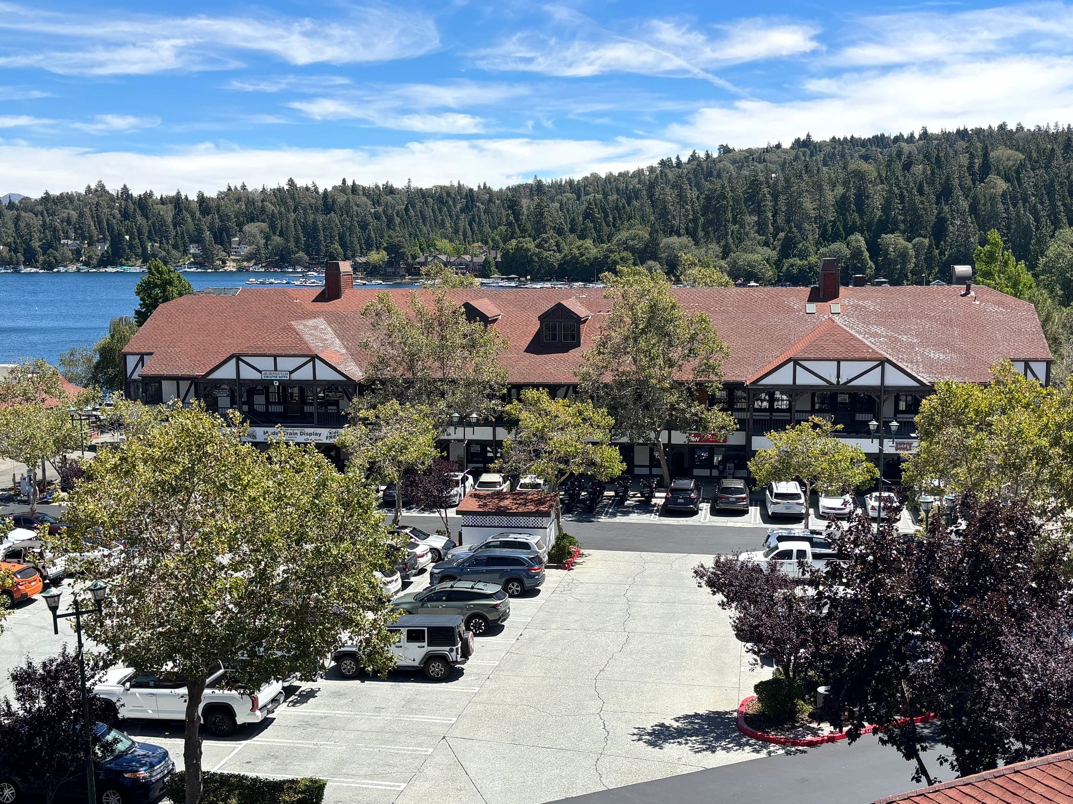 Tudor-style Lake Arrowhead Village buildings with the marina and forested hillside beyond