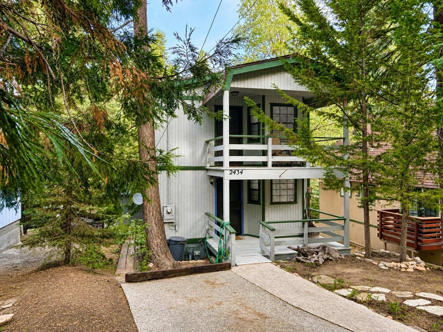 Front of 2434 Fir Drive with the house number, wood walkway, and pines along the street in Running Springs