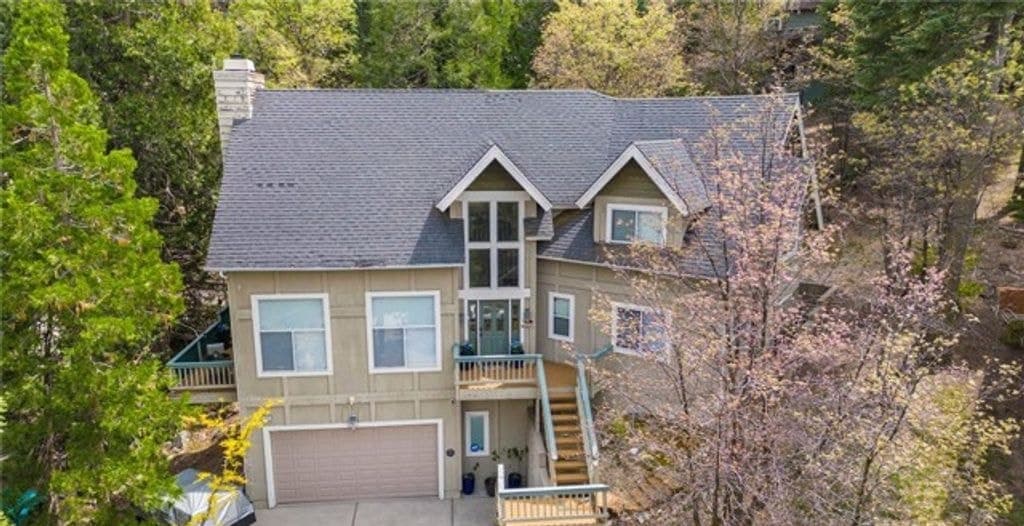 Aerial view of the two-story house and two-car garage among pines at 163 S Grass Valley, Lake Arrowhead