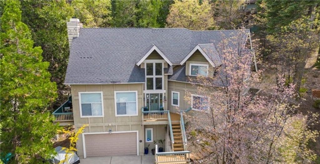 Aerial view of the two-story house and two-car garage among pines at 163 S Grass Valley, Lake Arrowhead