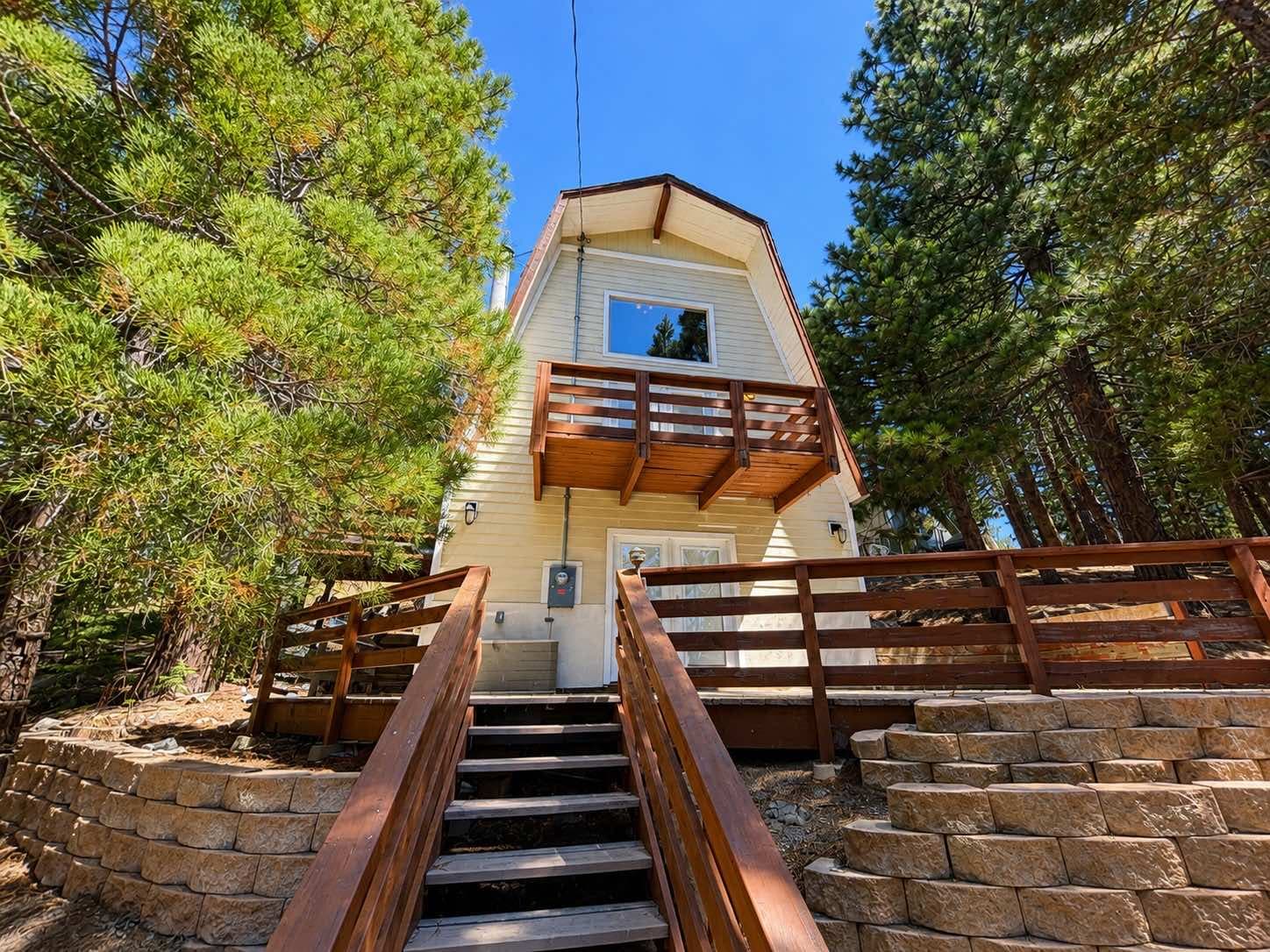 Pale yellow two-story mountain home with two dark wood decks among pines at 30975 Knob Hill Circle, Running Springs