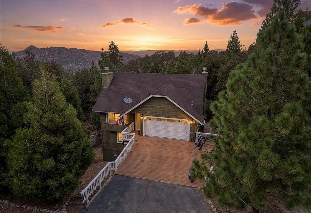 Aerial sunset view of 27398 Matterhorn Drive, a shingled mountain home surrounded by pines in Lake Arrowhead