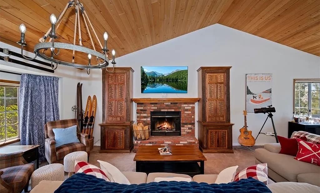 Vaulted great room with wood-plank ceiling, brick fireplace, and hand-carved cabinets at 27398 Matterhorn Drive