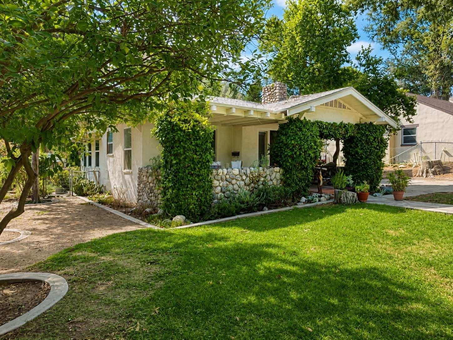 Side of the Banning cottage with a river-rock porch wall, chimney, and front lawn