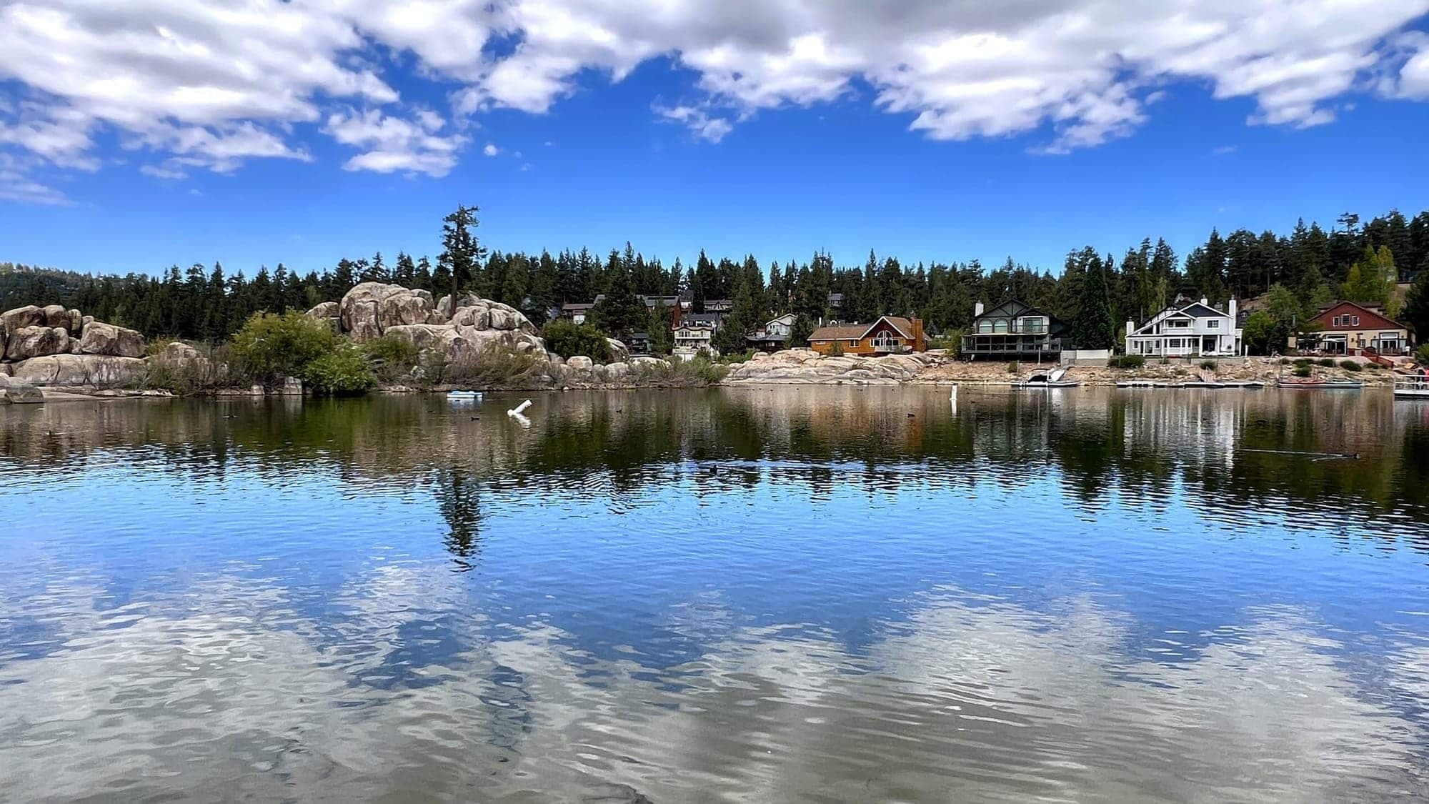 Calm Big Bear Lake reflecting pine trees and lakefront homes across the water