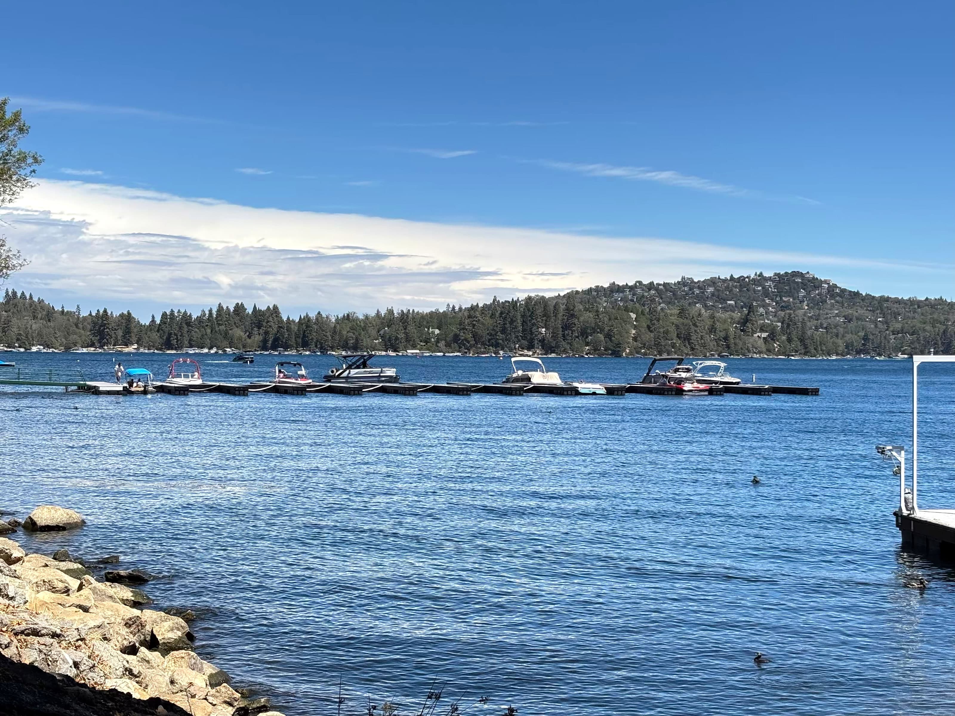 Pontoon boats at a Lake Arrowhead dock with forested mountains in the background