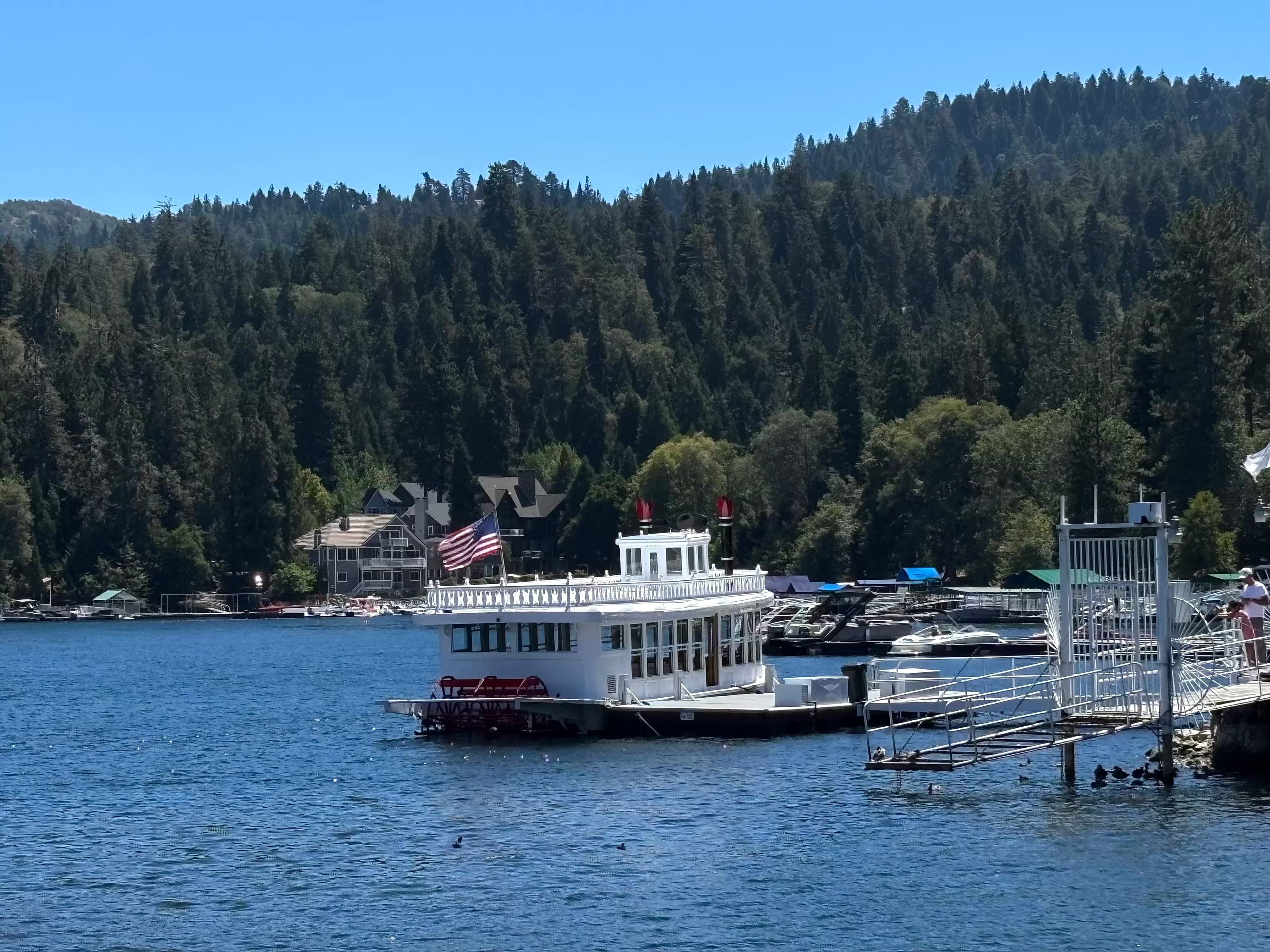 Lake Arrowhead Queen paddlewheeler with pine-covered shoreline and mountain homes