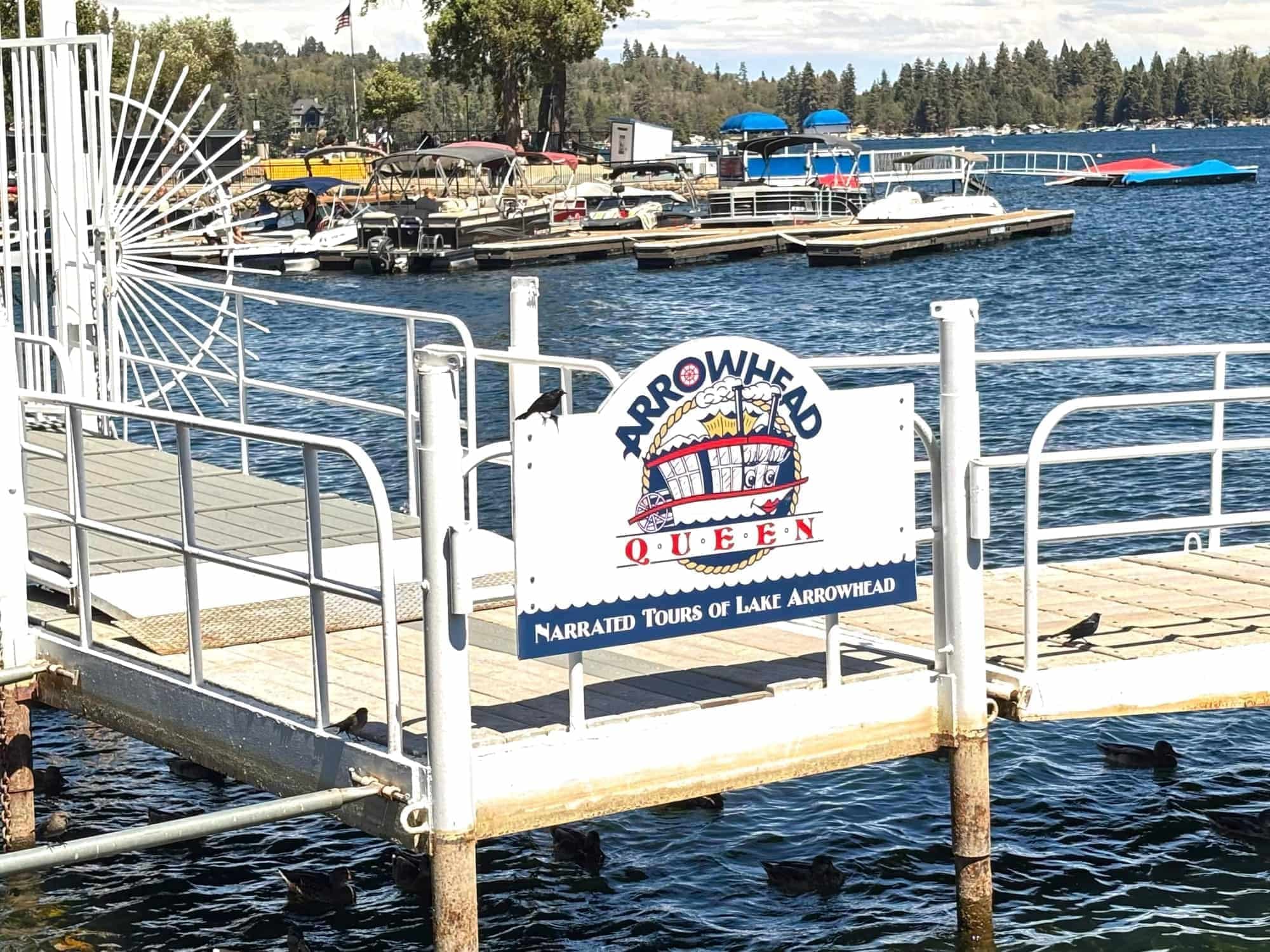 Arrowhead Queen narrated tours sign on a white dock at Lake Arrowhead