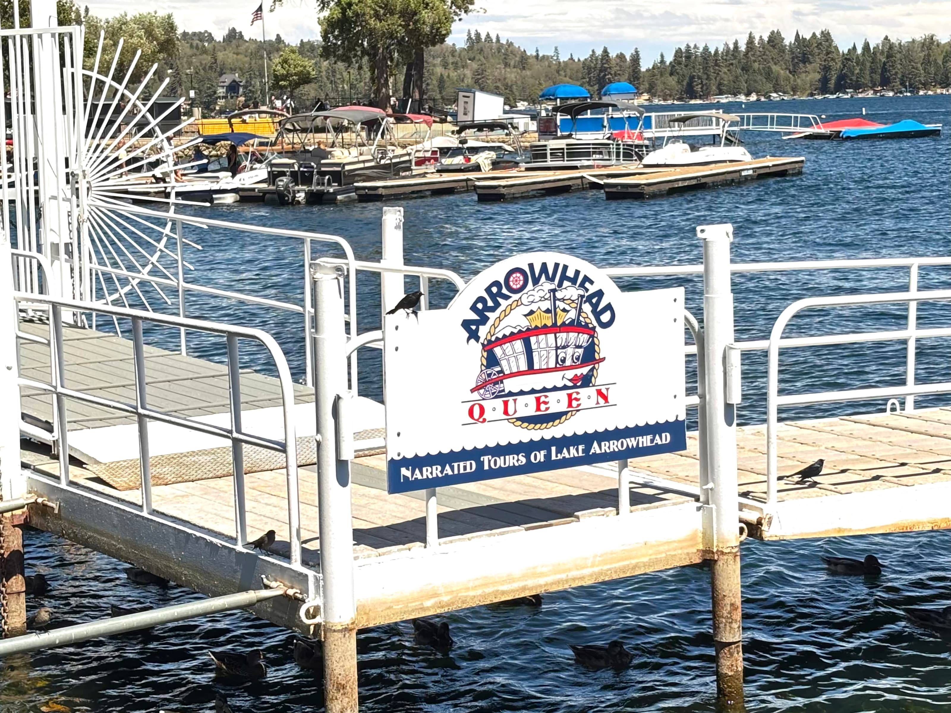 Arrowhead Queen narrated tours sign on a white dock at Lake Arrowhead