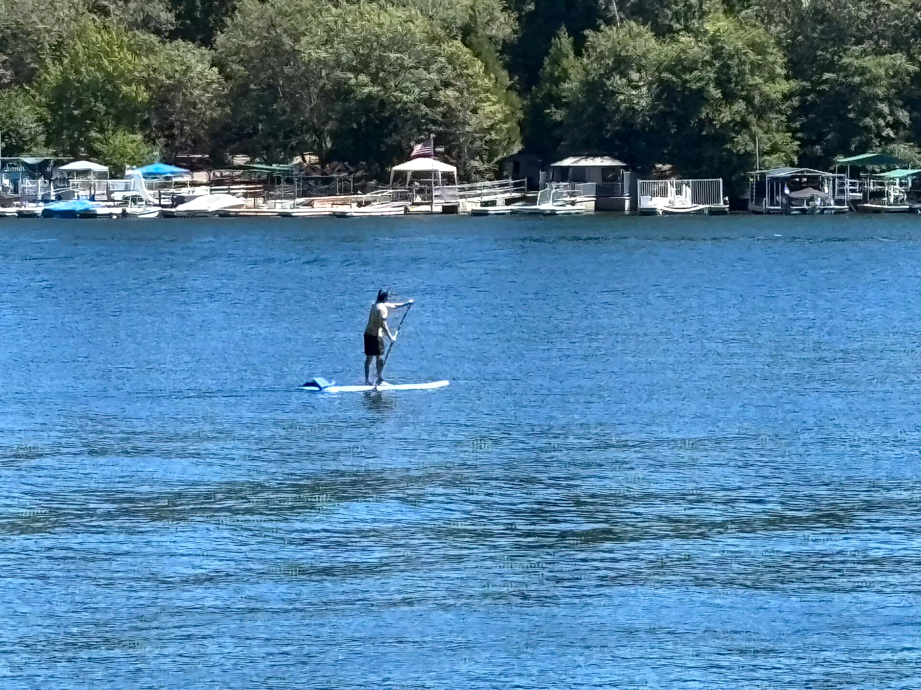 Stand-up paddleboarder on Lake Arrowhead in front of private shoreline docks