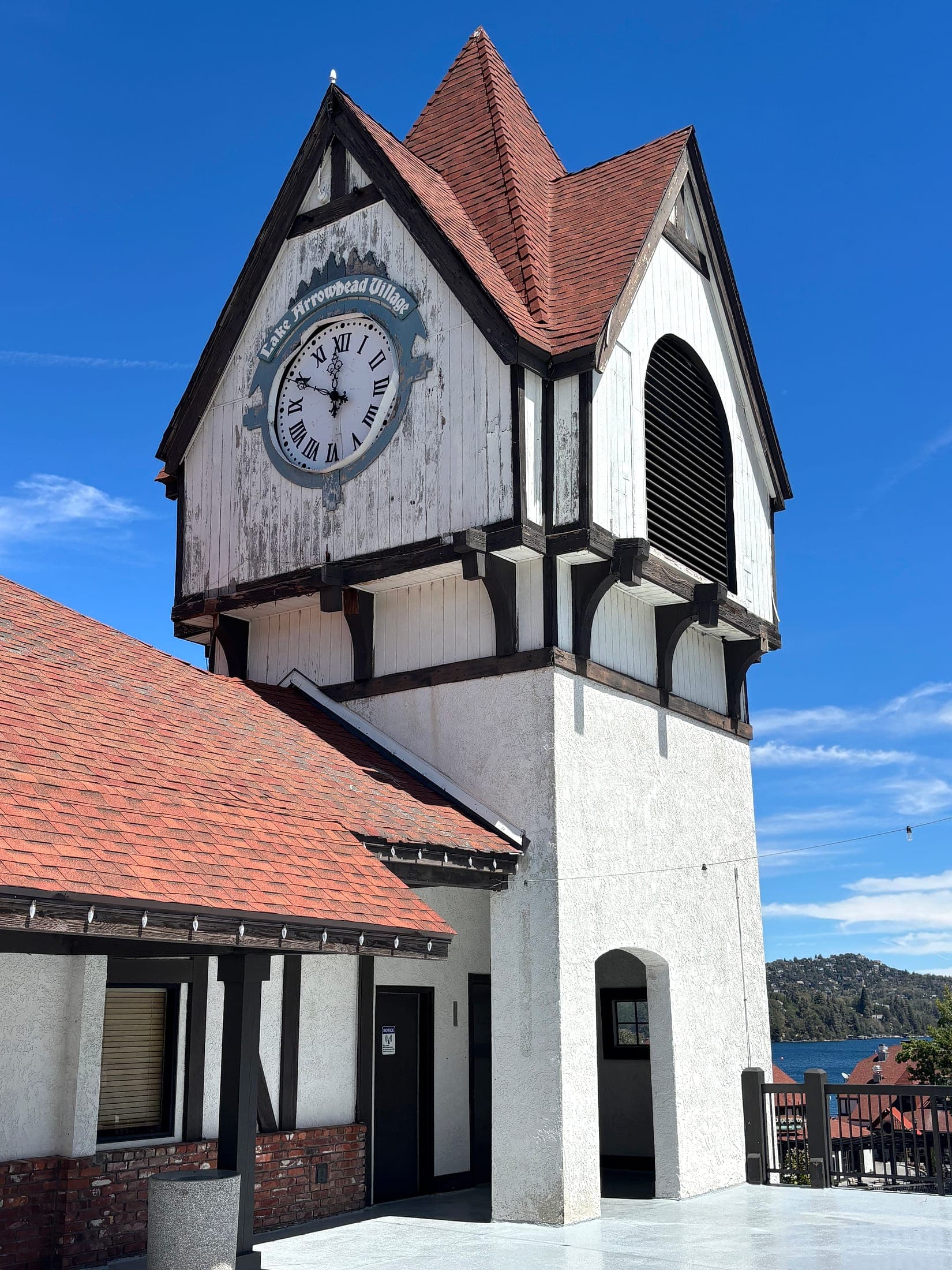 Lake Arrowhead Village clock tower with the lake and forested mountains in the distance