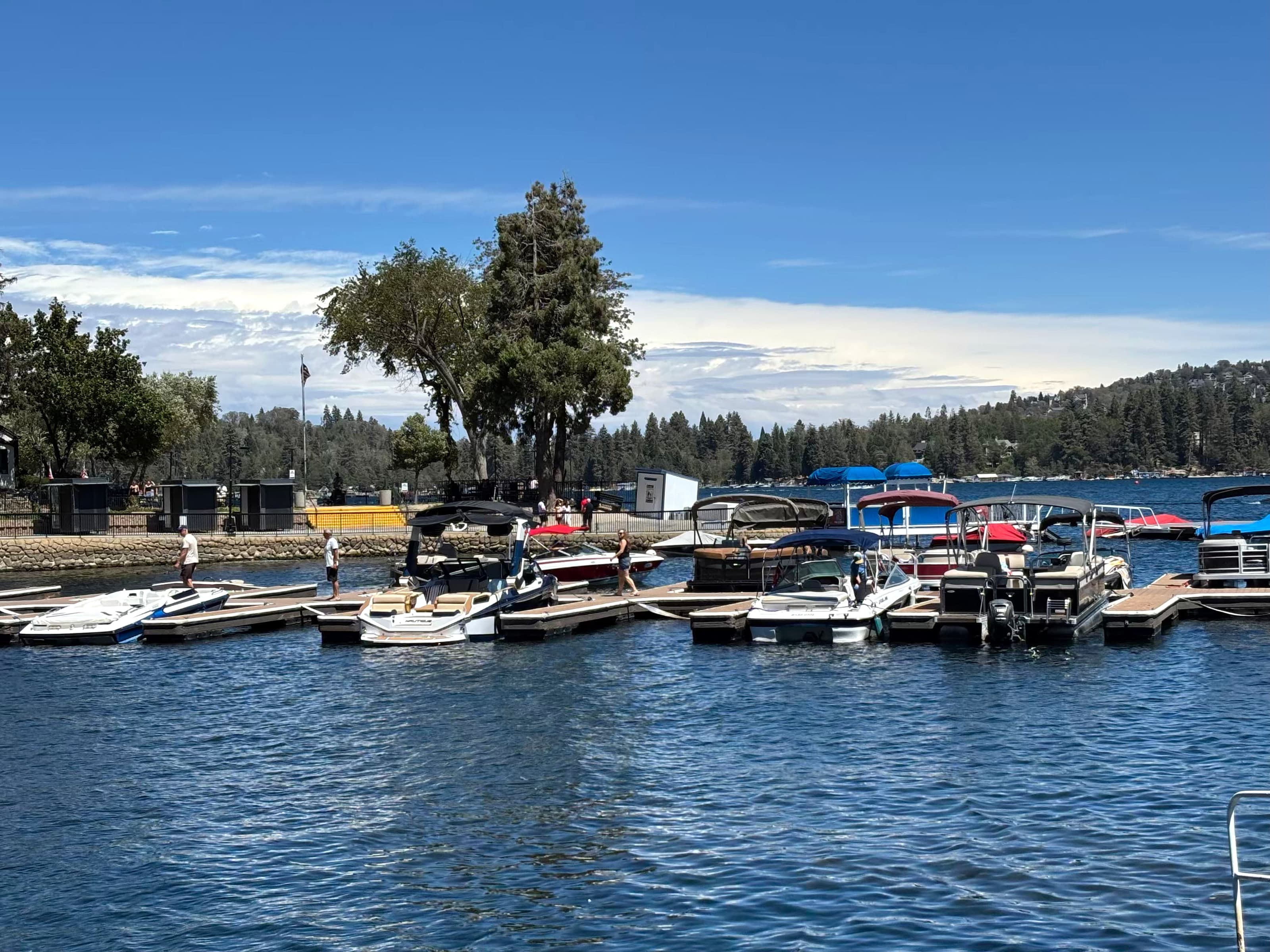 Boats at the Lake Arrowhead Village marina docks with forested hillside behind