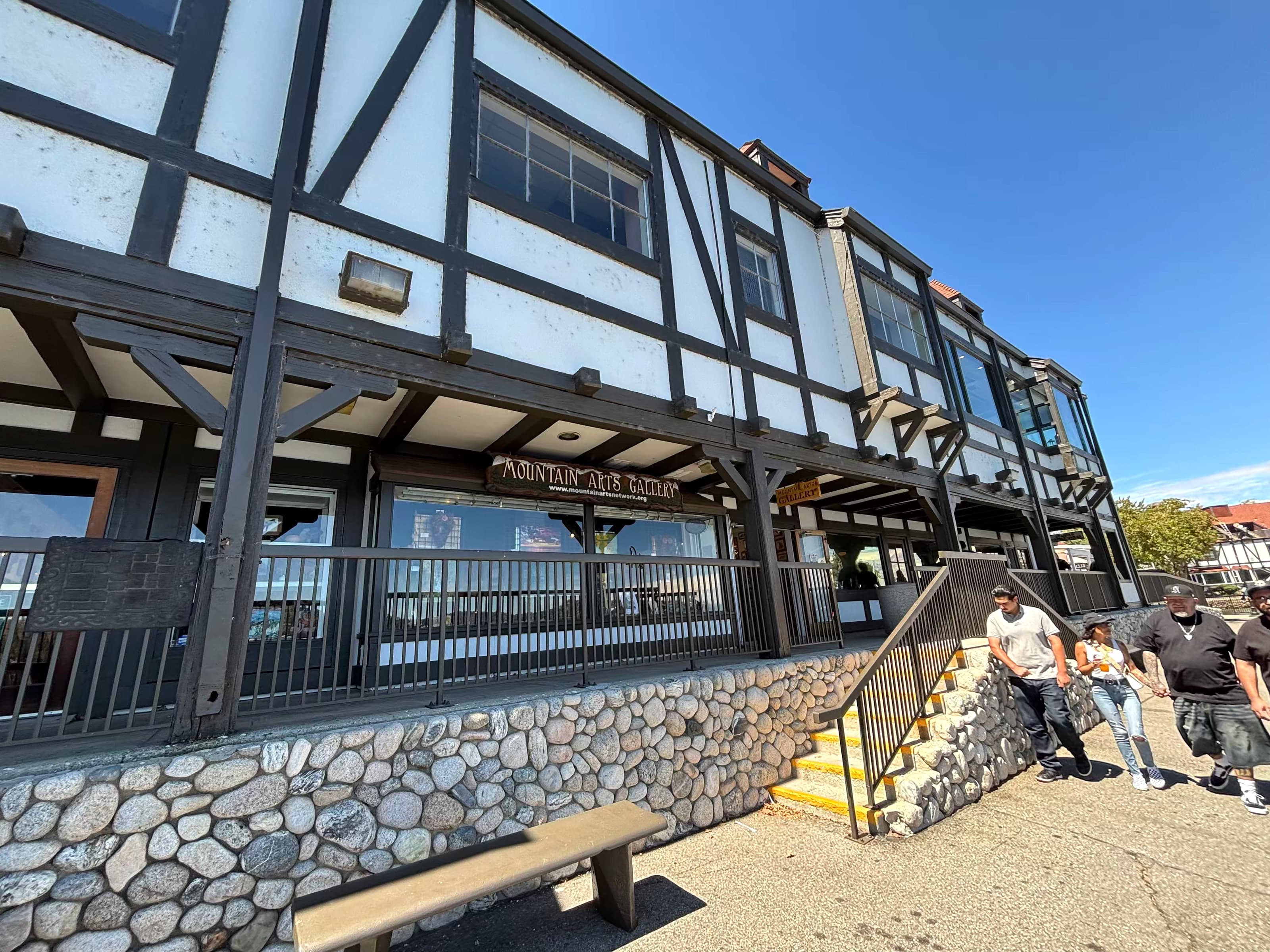 Tudor-style Lake Arrowhead Village building with stone base and Mountain Arts Network gallery sign