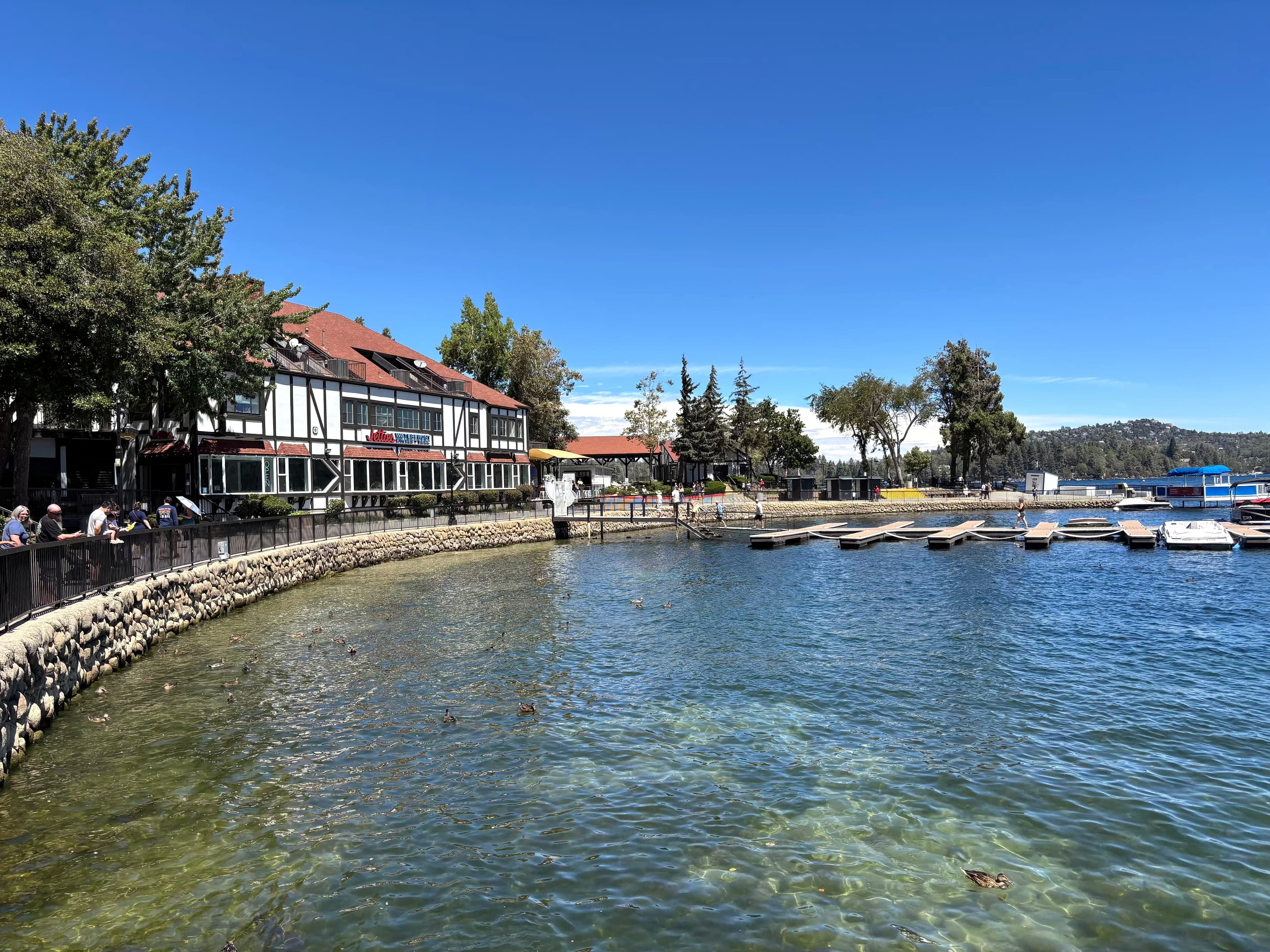 Tudor Lake Arrowhead Village building, stone shore path, and wooden docks on the lake