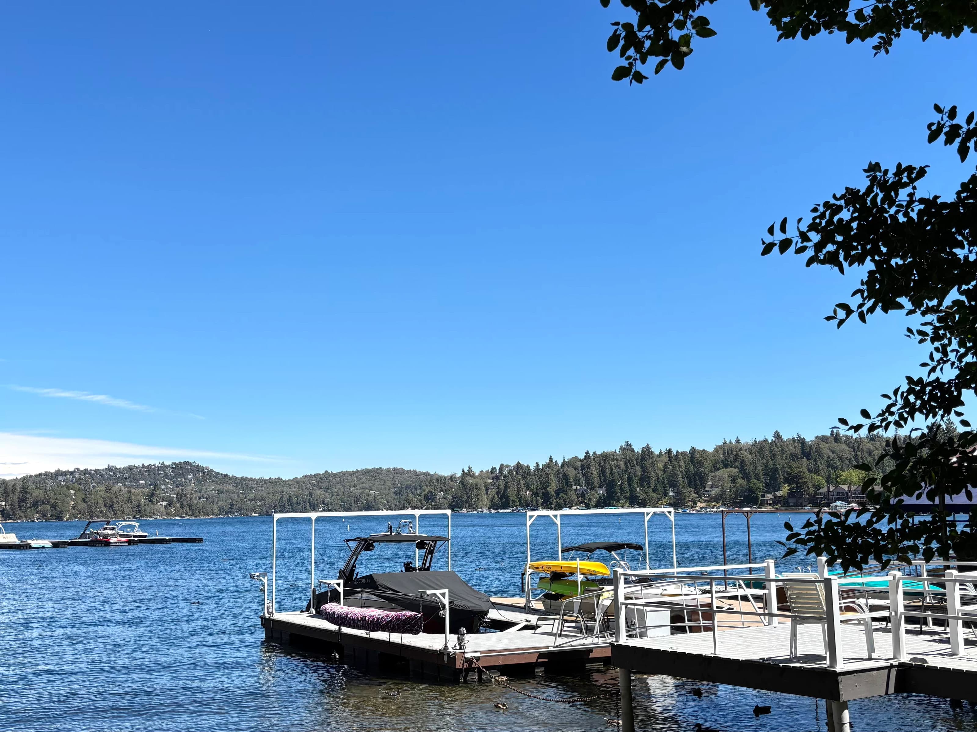 White boat dock and motorboat slip on Lake Arrowhead looking toward a forested shore