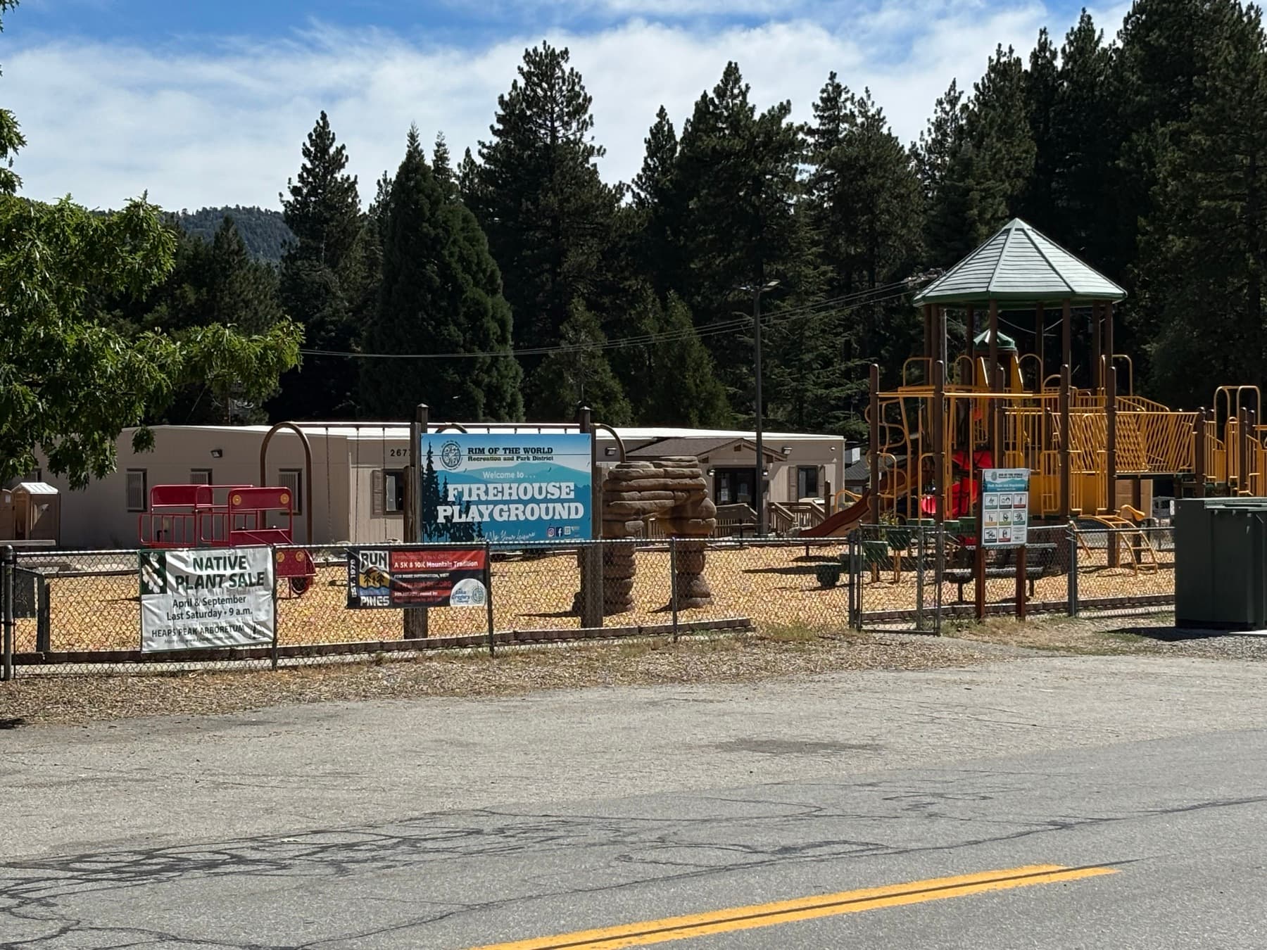 Firehouse Playground sign and play structure with pine trees, Rim of the World Recreation and Park District
