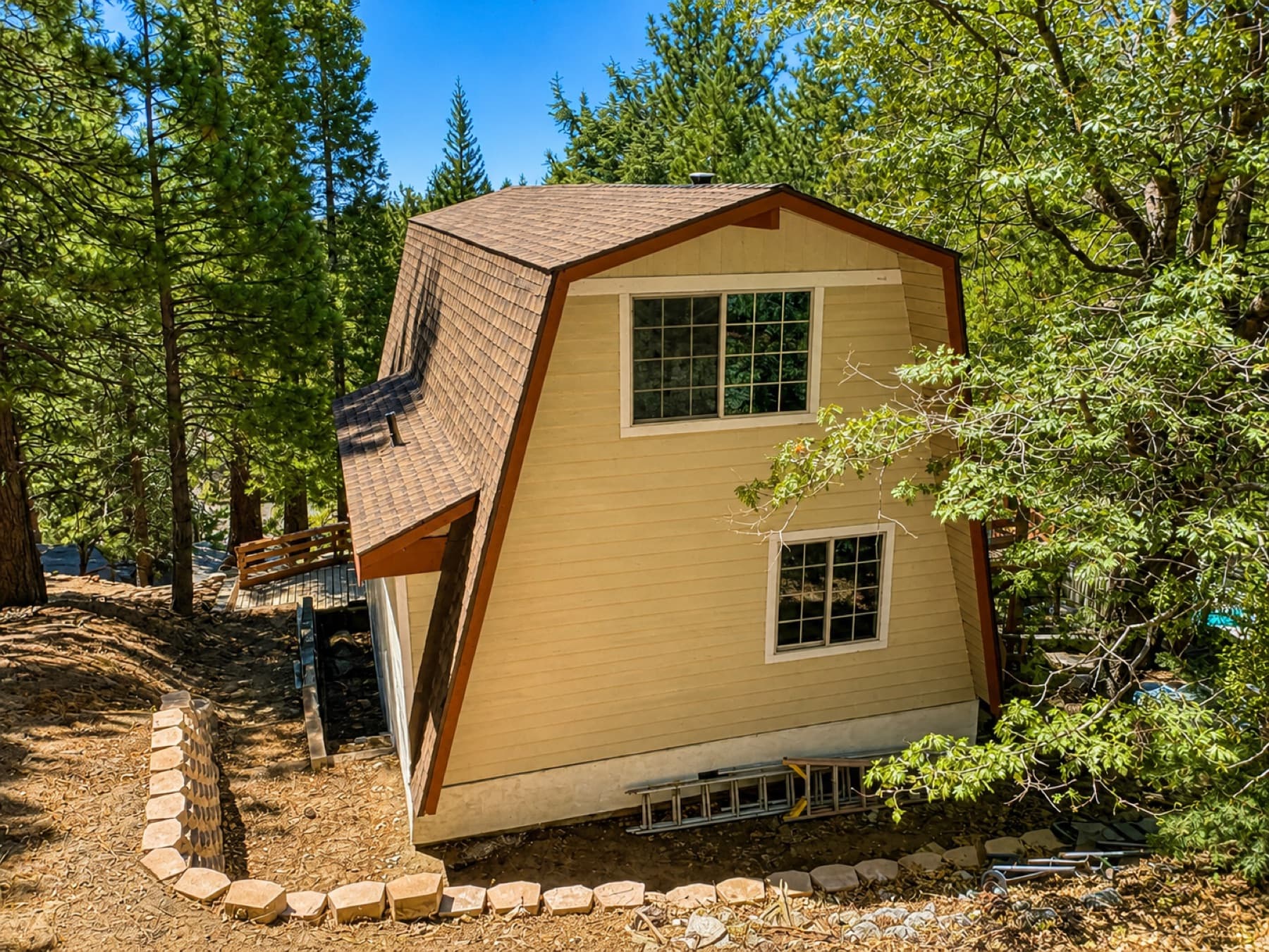 Side of a gambrel-roof mountain cabin among pines in Running Springs
