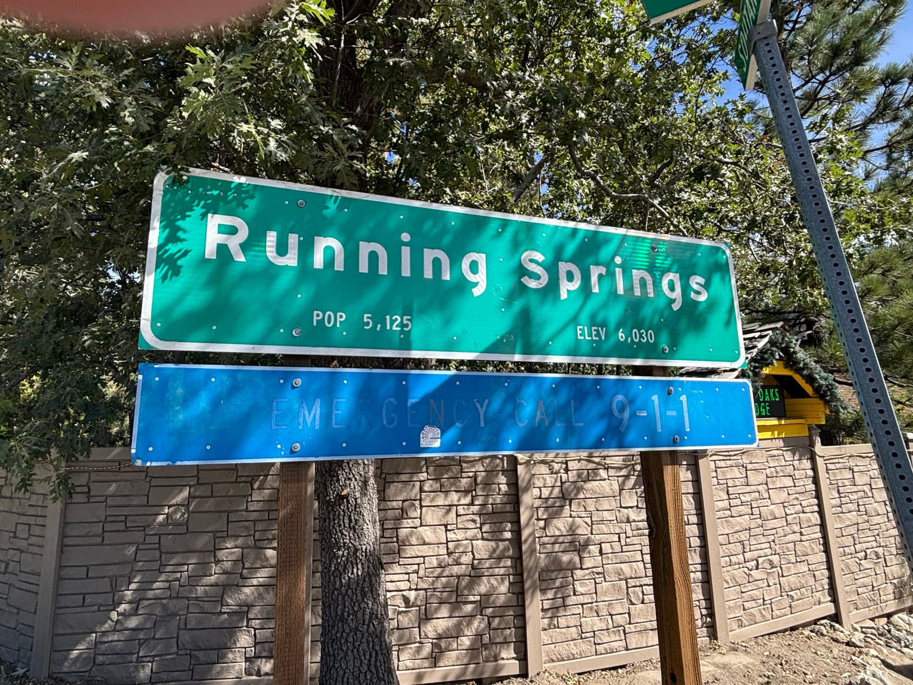 Green Running Springs community sign listing population and elevation, with trees behind it