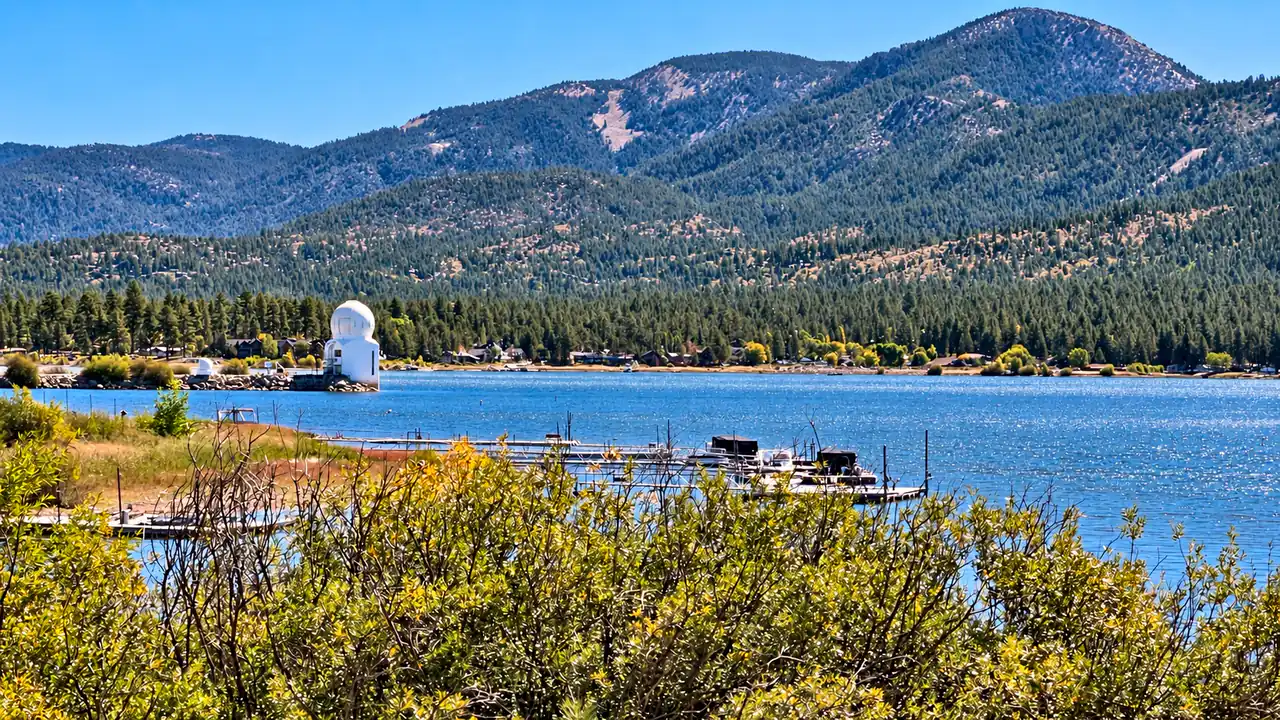 Small boat docks on Big Bear Lake, with pine-covered mountains and distant shoreline houses
